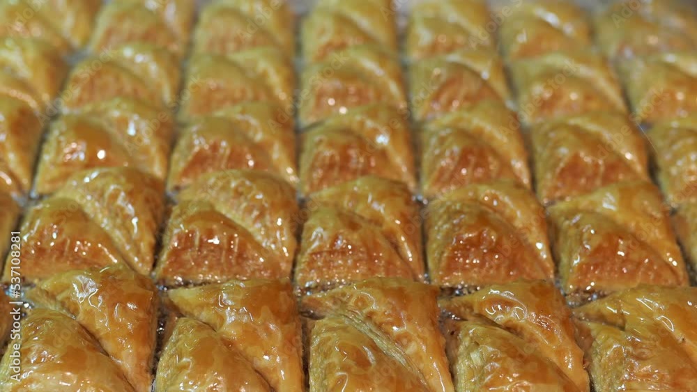 Pouring sweet syrup on Turkish Baklava with Dessert with layered pastry, filled with chopped nuts, and sweetened with syrup or honey. Pouring sweet syrup on Turkish Baklava with Dessert with layered pastry, filled with chopped nuts, and sweetened with syrup or honey.