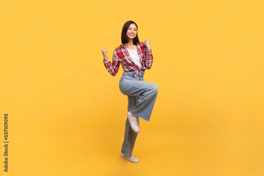 Excited asian lady celebrating success and jumping in air, happy having fun over yellow studio background, full length Excited asian lady celebrating success and jumping in air, happy having fun over yellow studio background, full length