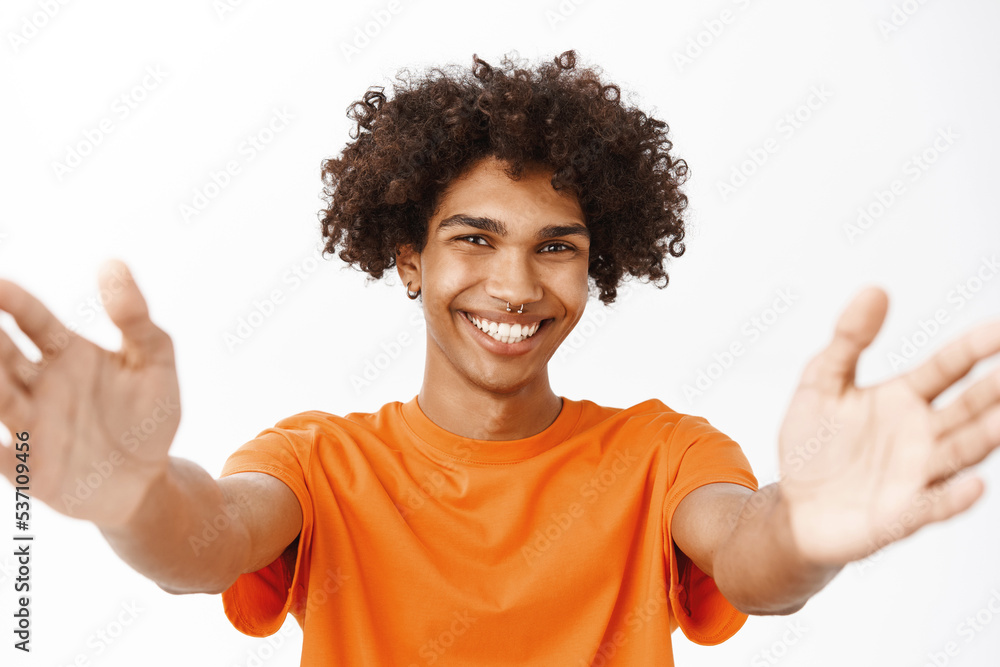 Close up portrait of smiling hispanic man reaching out his hands, stretching arms, holding something, standing over white background Close up portrait of smiling hispanic man reaching out his hands, stretching arms, holding something, standing over white background