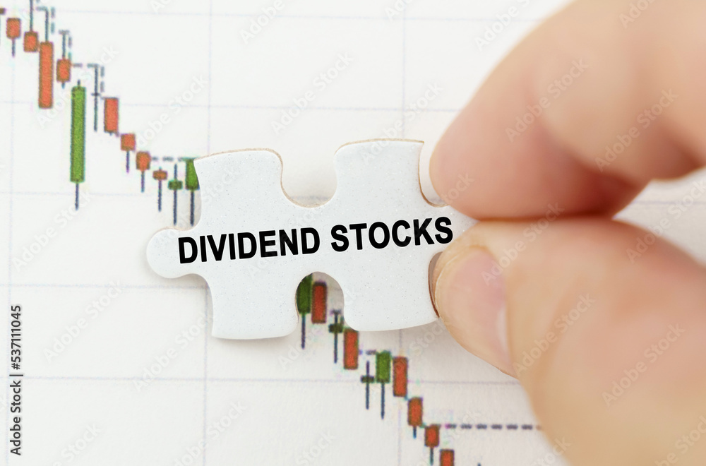 Against the background of the quotes chart, a puzzle with the inscription - Dividend stocks Against the background of the quotes chart, a puzzle with the inscription - Dividend stocks