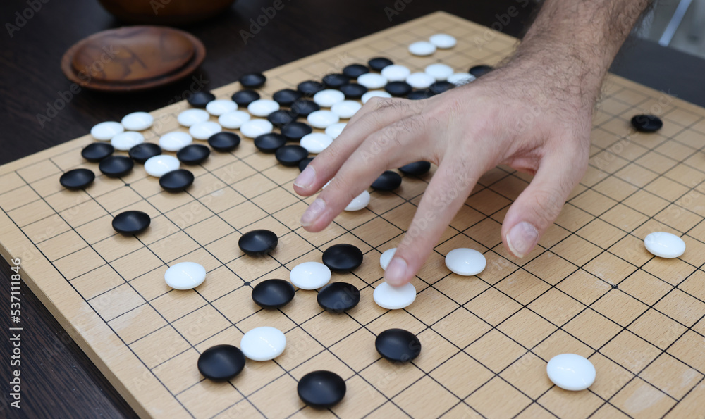 Young people move black and white stones while playing go Young people move black and white stones while playing go