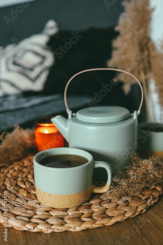 Cup of tea, kettle and burning candle in bedroom, home interior