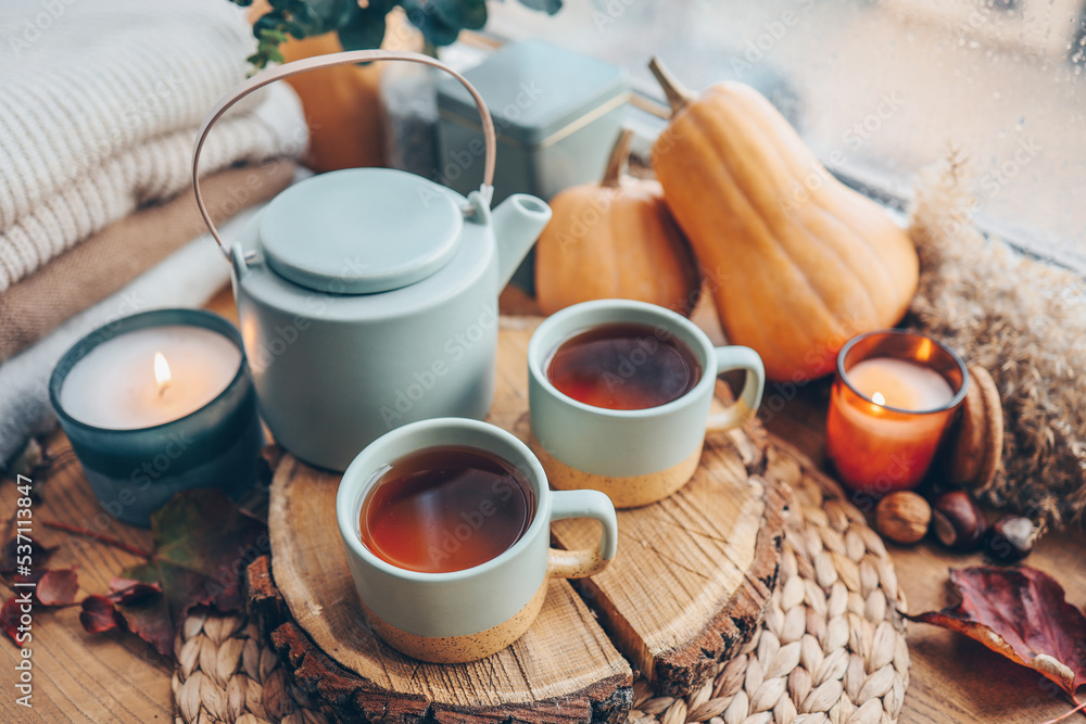 Beautiful autumn composition with burning candles and cup of tea on window sill Beautiful autumn composition with burning candles and cup of tea on window sill