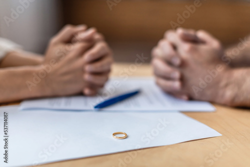 Foto Hands of sad middle aged european man and woman on divorce papers and ring on ta