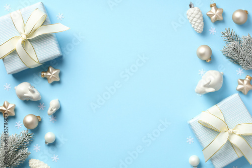 Christmas flat lay composition with present boxes and beige decorations on pastel blue background.