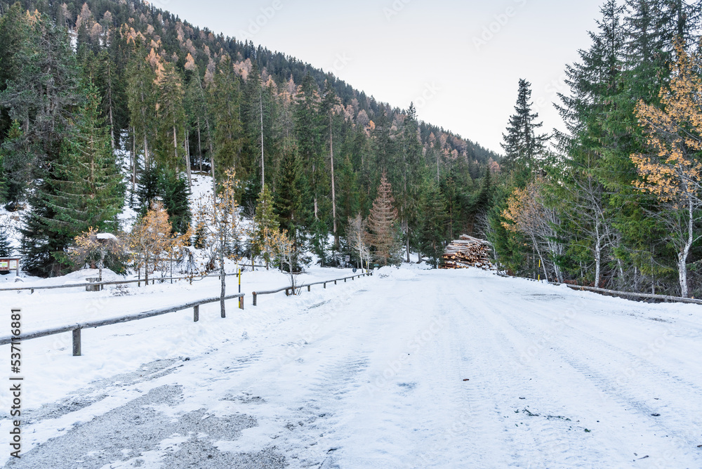 Empty snowy parking lot at the foot of a forested slope in the mountains in autumn