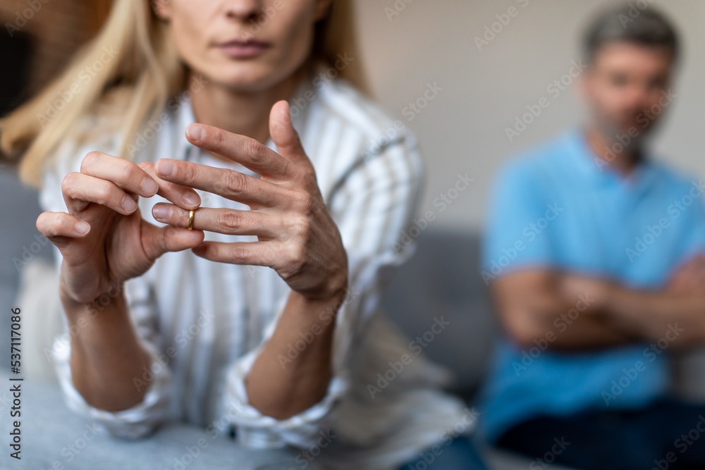 Unhappy middle aged european lady takes off ring, ignoring man during quarrel in living room interior