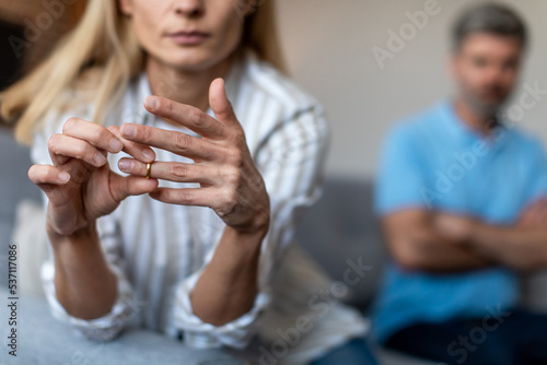 Unhappy middle aged european lady takes off ring, ignoring man during quarrel in living room interior