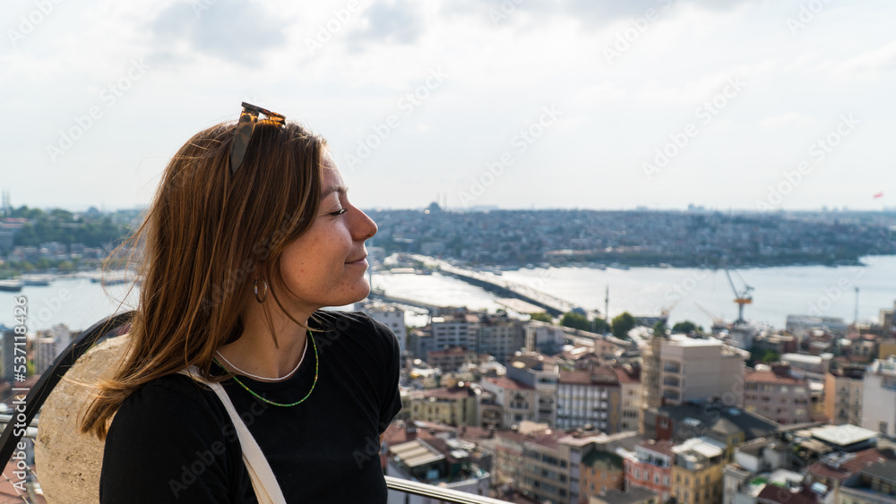 Young tourist woman sightseeing with Istanbul landscape at sunset. Young beautiful woman watching Istanbul from the Galata Tower