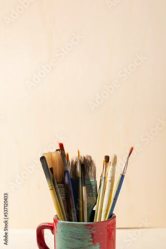 used brushes inside a pot, on wooden background 