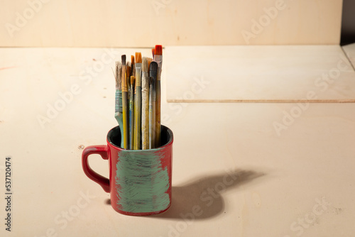 used brushes inside a pot, on wooden background
