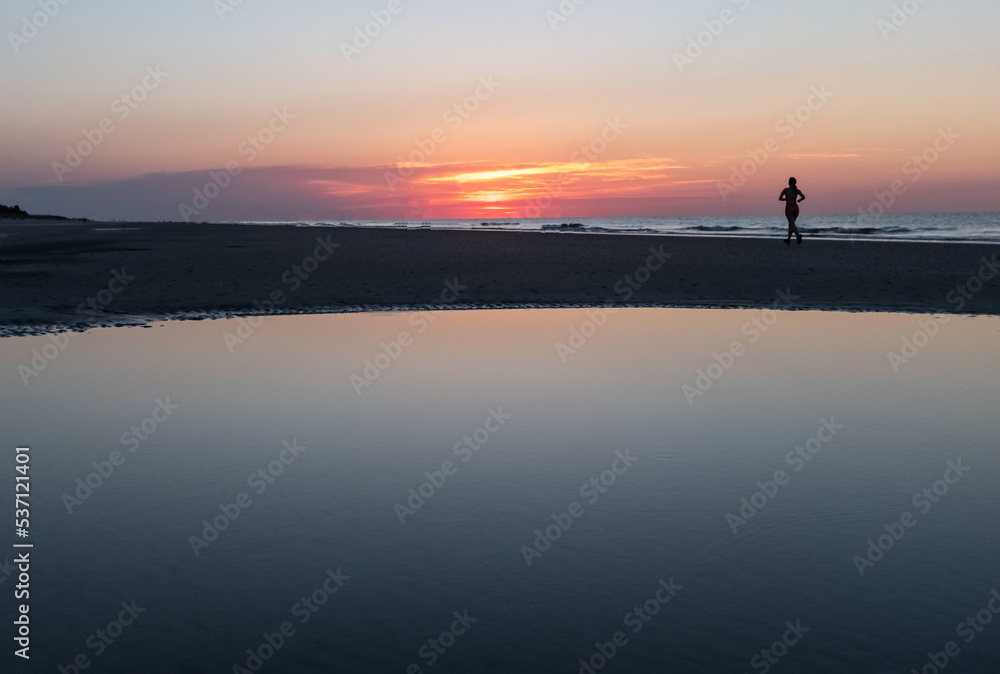 silhouette of a woman running on Coligny Beach, Hilton Head Island, south Carolina.