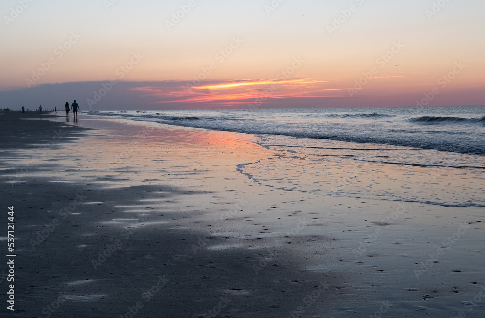 Couple walking at sunrise on Coligny Beach, Hilton Head Island, South Carolina.