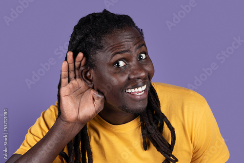 Excited young black man holding hand next to ear