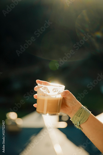 Hand of a girl holding a glass of coffee during morning