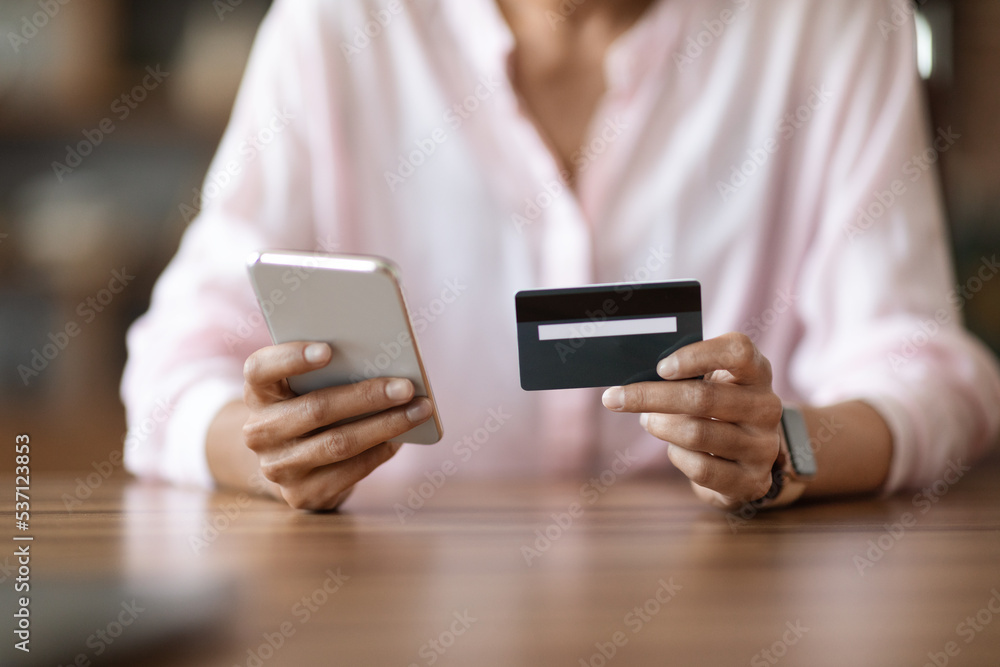 Cropped of woman holding cell phone and credit card Cropped of woman holding cell phone and credit card