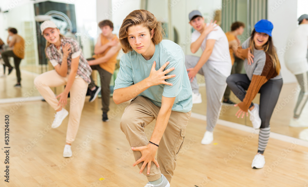 Group of positive teenagers dancing modern dance in ballroom.