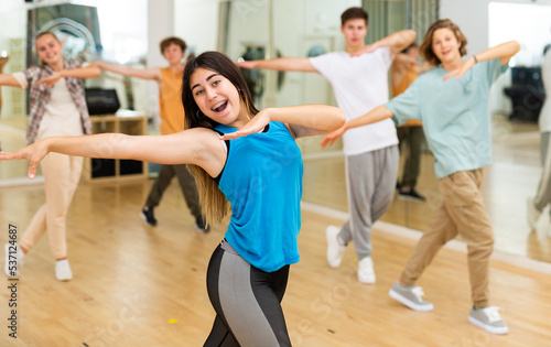 Group of active teens rehearsing modern dance in studio.