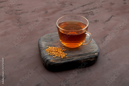Helba drink or fenugreek yellow tea on wooden board on brown background. Methi Dana drink. Herbal tea. Alternative medicine