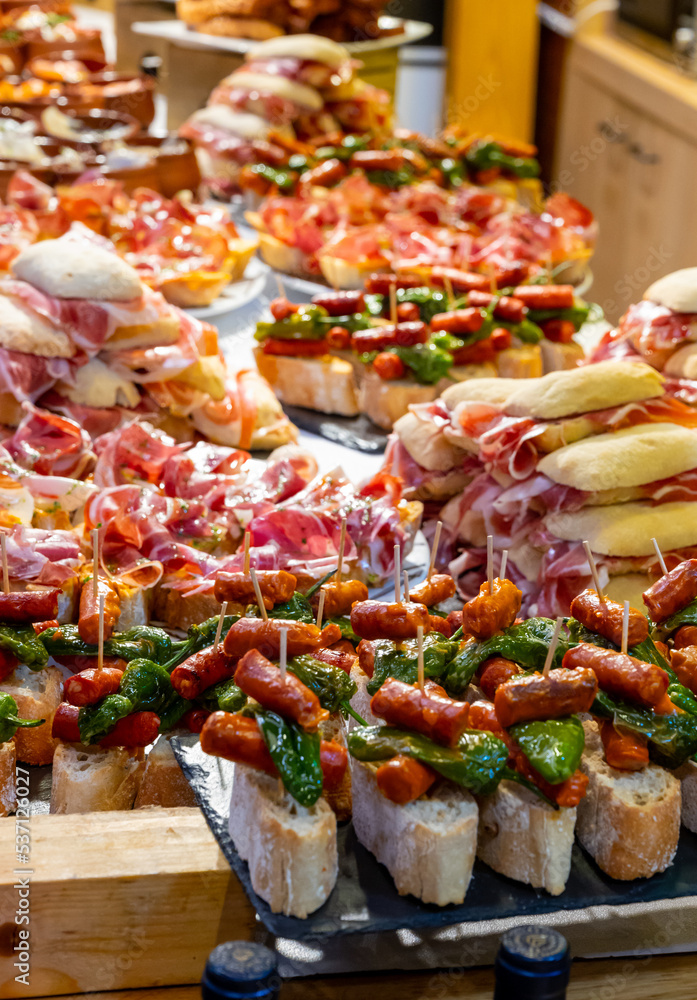 Typical snack of Basque Country and Navarre, pinchos or pinxtos, small piece of bread with different toppings, served in bar, Bilbao, Spain Typical snack of Basque Country and Navarre, pinchos or pinxtos, small piece of bread with different toppings, served in bar, Bilbao, Spain