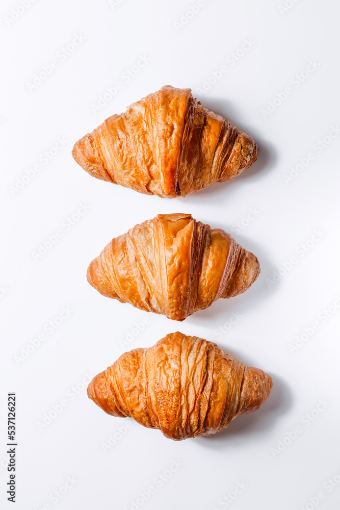 Three fresh golden croissants on a white background view from above. Creative end of baking and breakfast Three fresh golden croissants on a white background view from above. Creative end of baking and breakfast