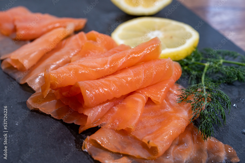 Slices of tasty smoked Scottish salmon fish served on black plate with lemon and fresh dill Slices of tasty smoked Scottish salmon fish served on black plate with lemon and fresh dill