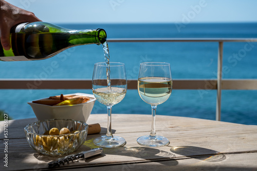 Pouring of txakoli or chacol   slightly sparkling very dry white wine produced in the Spanish Basque Country  served outdoor with view on Bay of Biscay  Atlantic Ocean.