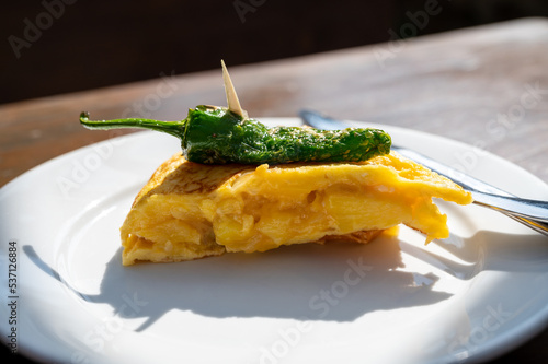 Typical snack in bars of Basque Country, pinchos or pinxtos, small slices of bread withn different toppings and fastened with skewers, San Sebastian, Spain. Potato tortilla with green pepper. photo