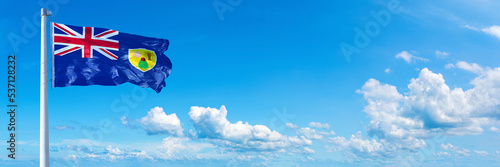 Turks and Caicos Islands flag waving on a blue sky in beautiful clouds - Horizontal banner
 photo