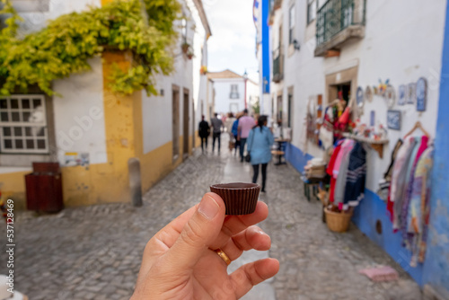 Φωτογραφία Men hand holding the traditional Ginja de Obidos, traditional sour cherry liquor, served in small cups made of chocolate