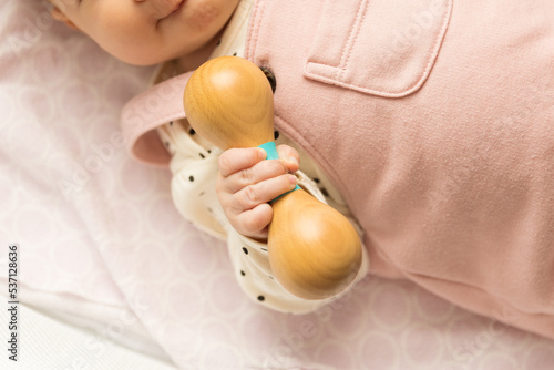 Baby holding a wooden rattle toy photo