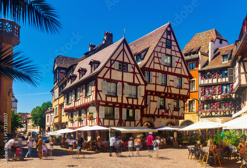 View of historic center of French city of Colmar with paved streets and picturesque half-timbered houses painted in traditional Alsatian colors in summer