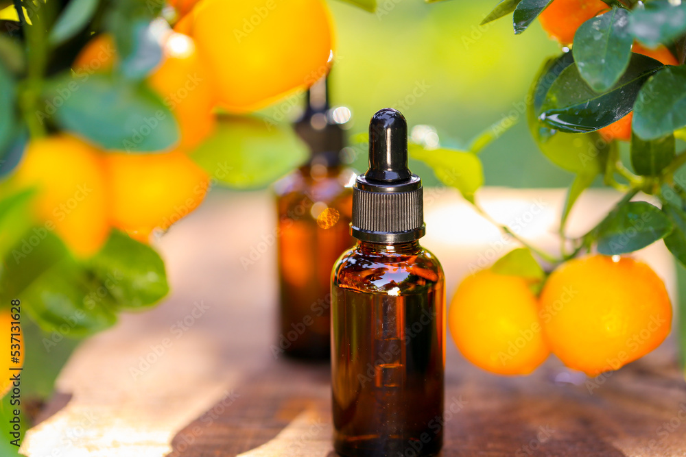 Mandarin oil.tangerine essential oil.Natural organic pure oil. brown bottles with oil on a brown wood background and tangerines with green leaves.Organic natural eco cosmetics. Mandarin oil.tangerine essential oil.Natural organic pure oil. brown bottles with oil on a brown wood background and tangerines with green leaves.Organic natural eco cosmetics.