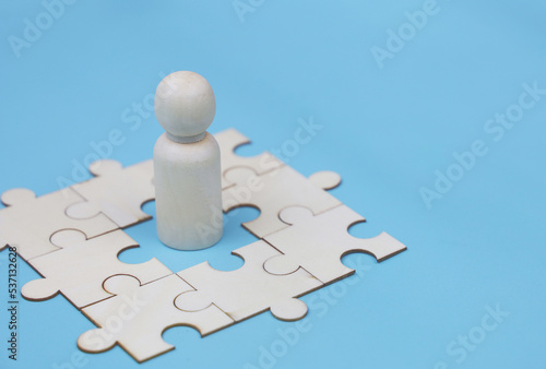 Wooden peg dolls with wooden puzzle.The concept of choosing leaders for business success. Organization development. Leadership. Personnel selection. Wooden puppet. Wooden peg dolls.