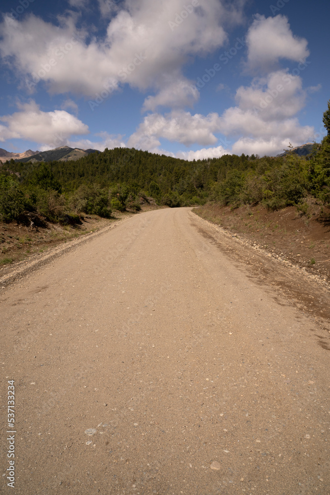 Driving along the dirt road across the mountains and forest in a sunny day. 