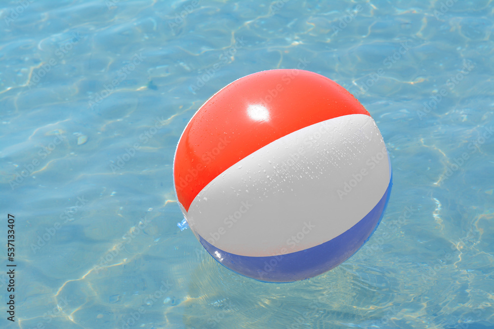 Colorful beach ball floating in sea on sunny day