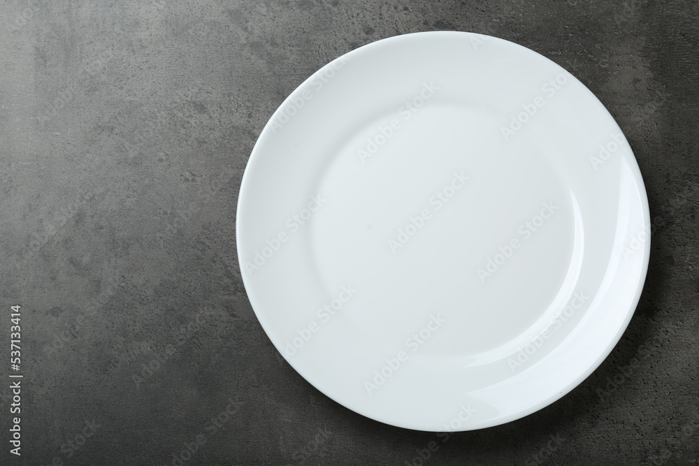 Empty white ceramic plate on grey table, top view. Space for text Empty white ceramic plate on grey table, top view. Space for text