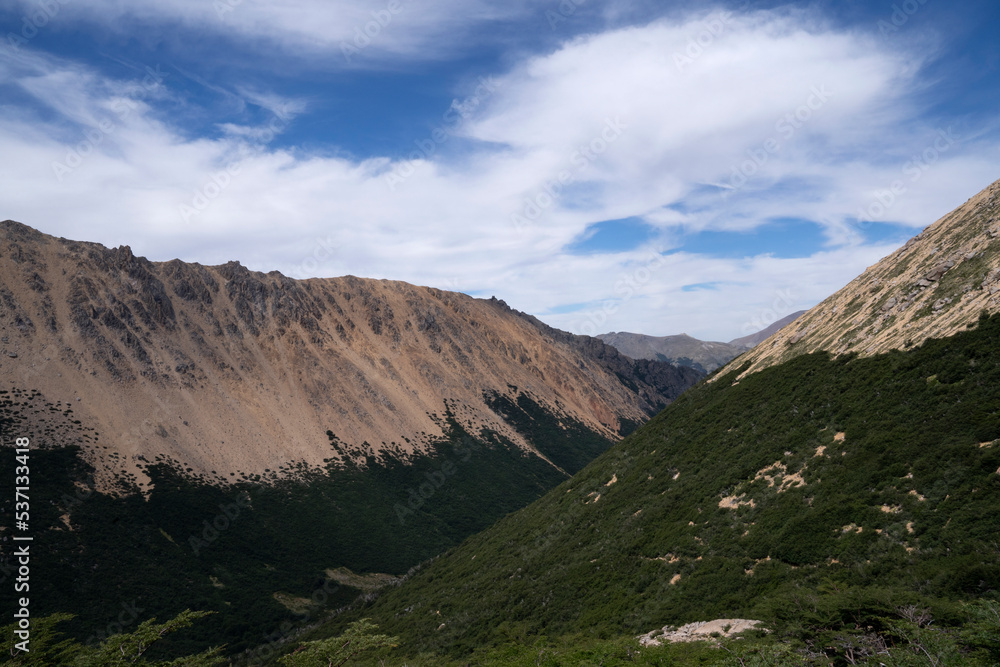 Alpine landscape. Hiking in the mountains. Panorama view of the hills, valley and forest under a beautiful sky with clouds. Alpine landscape. Hiking in the mountains. Panorama view of the hills, valley and forest under a beautiful sky with clouds.