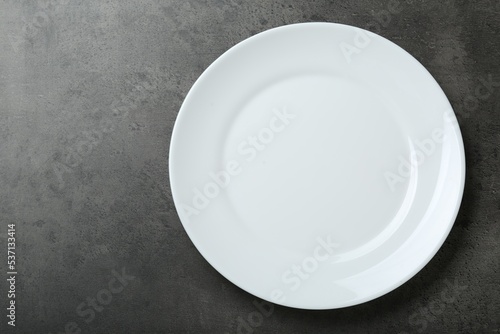 Empty white ceramic plate on grey table, top view. Space for text