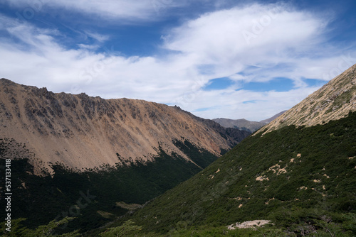 Alpine landscape. Hiking in the mountains. Panorama view of the hills  valley and forest under a beautiful sky with clouds. 