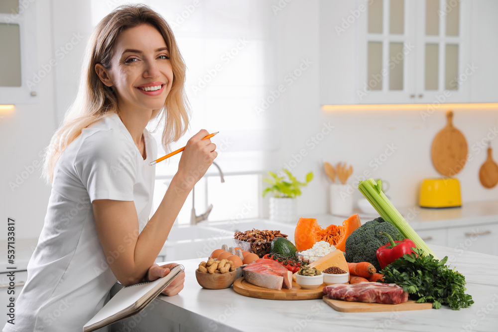 Woman with notebook and healthy food at white table in kitchen. Keto diet - obrazy, fototapety, plakaty 