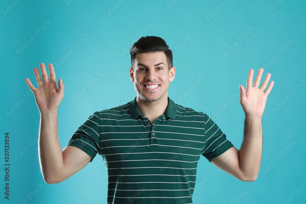 Naklejka premium Cheerful man waving to say hello on turquoise background