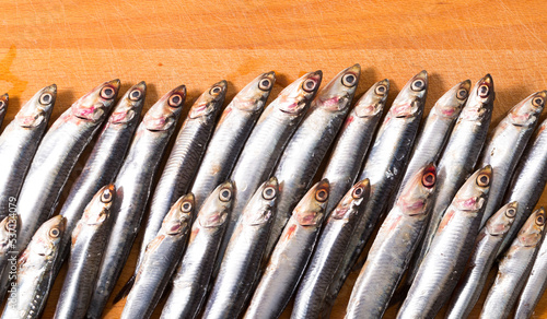 Closeup of pickled European anchovies on wooden background.. photo