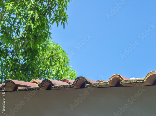 orange tile roof. corrugated side of the roof. details of the top cover of the house made of clay on a blue sky background with lush and cool trees