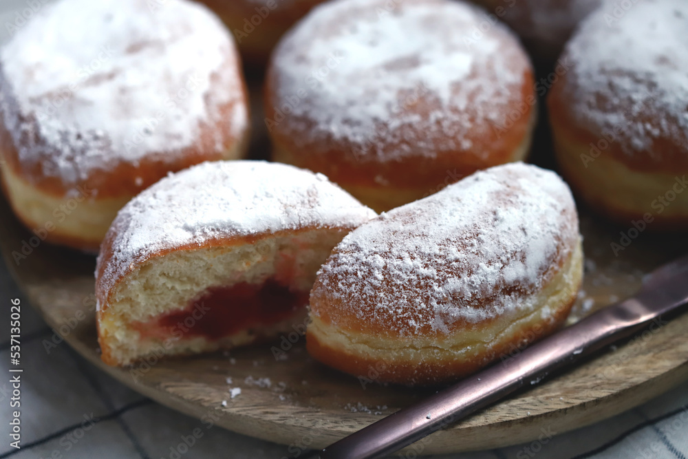 Fototapeta premium Berliner donuts in powdered sugar on a wooden tray.