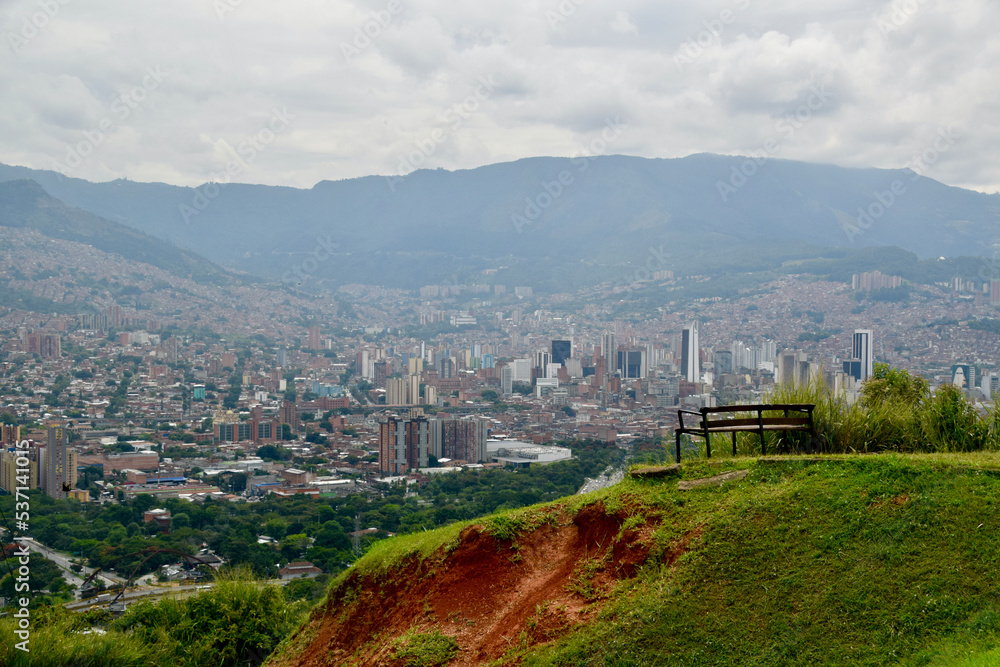 city view of Medellín from the Volador with a wooden bench on green grass in front