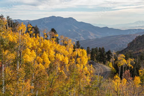 A white truck drives around a curving road high in the mountains of Utah on the Nebo Loop during autumn. 