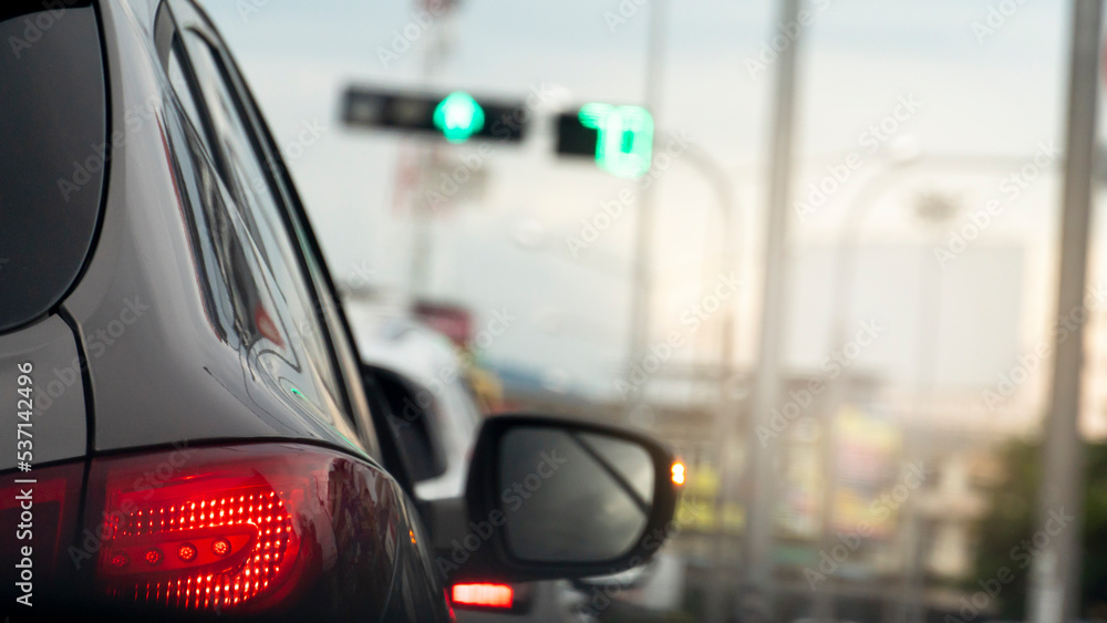 Rear side of gray car in the dark tone. Background and blurred of traffic on the road with a green traffic light in the city. Rear side of gray car in the dark tone. Background and blurred of traffic on the road with a green traffic light in the city.