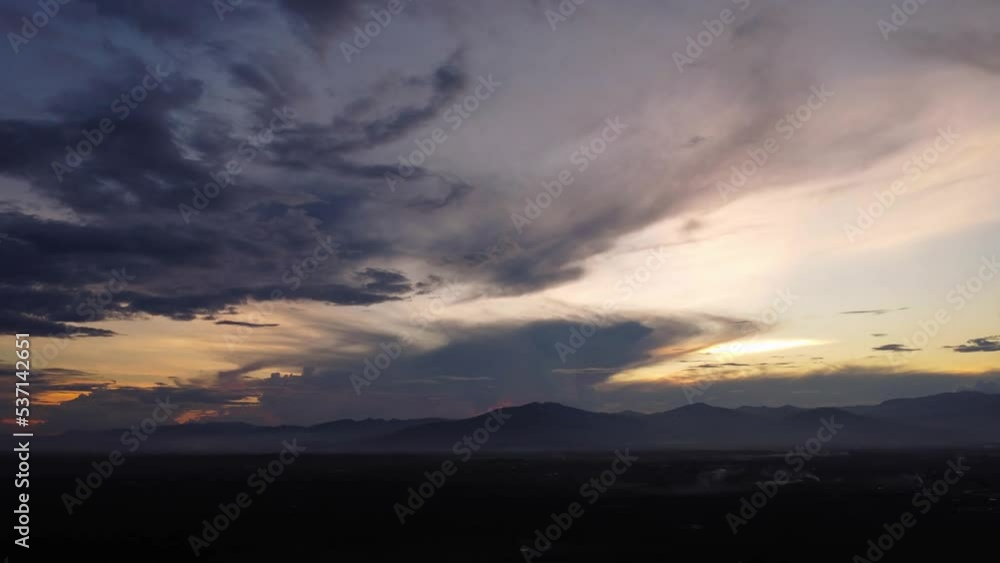 Aerial view of beautiful sky with clouds and sunlight during sunset. Time lapse of the clouds above the sky with the golden rays of the sun against the background of the silhouette of the mountain lan Aerial view of beautiful sky with clouds and sunlight during sunset. Time lapse of the clouds above the sky with the golden rays of the sun against the background of the silhouette of the mountain lan