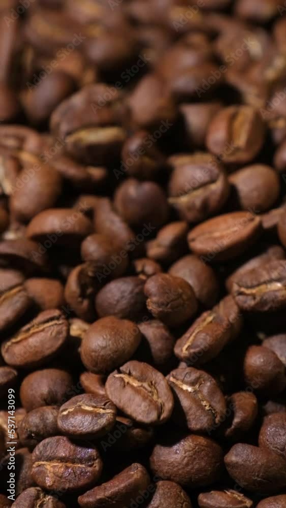 Vertical slow motion of roasted coffee beans falling. Organic coffee seeds. Vertical slow motion of roasted coffee beans falling. Organic coffee seeds.